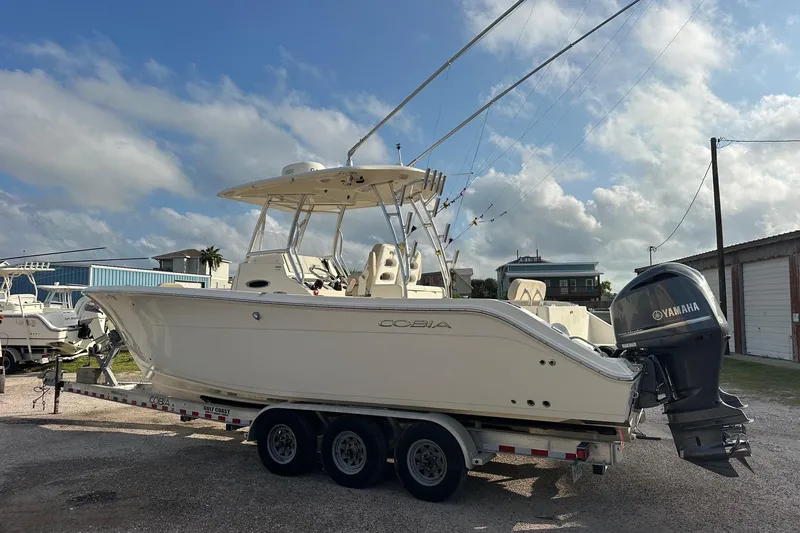 Slide: The Image of 2016 Cobia 296 Center Console boat on trailer with Yamaha engines, under a partly cloudy sky. - 5