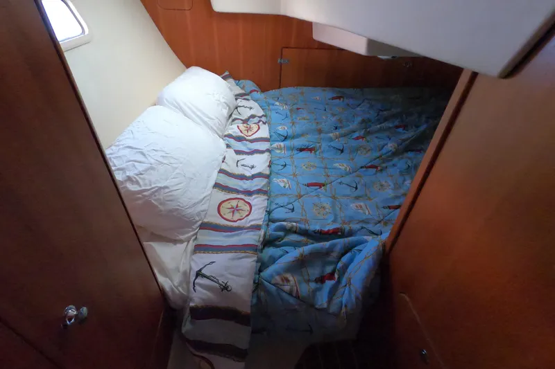 Slide: The Image of Cozy cabin bed in 2006 Hunter 33 sailboat with nautical-themed bedding. - 13