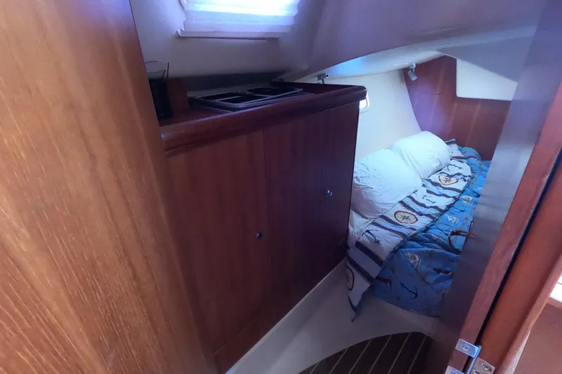 Slide: The Image of Cozy cabin interior of 2006 Hunter 33 sailboat with wooden cabinetry and bed. - 14