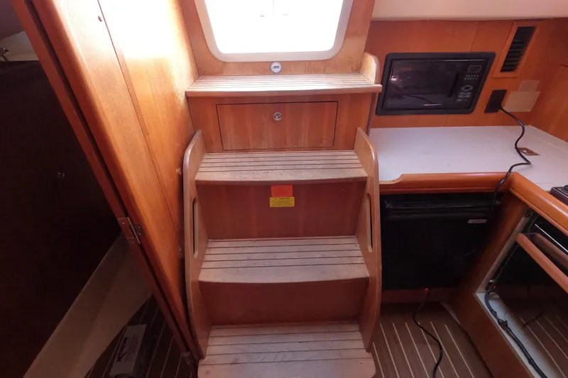 Slide: The Image of Interior of a 2006 Hunter 33 sailboat with wooden steps and compact kitchen area. - 27