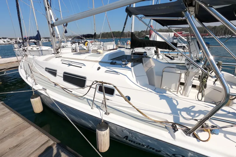 Slide: The Image of 2006 Hunter 33 sailboat docked at marina, featuring sleek white design and spacious deck. - 3