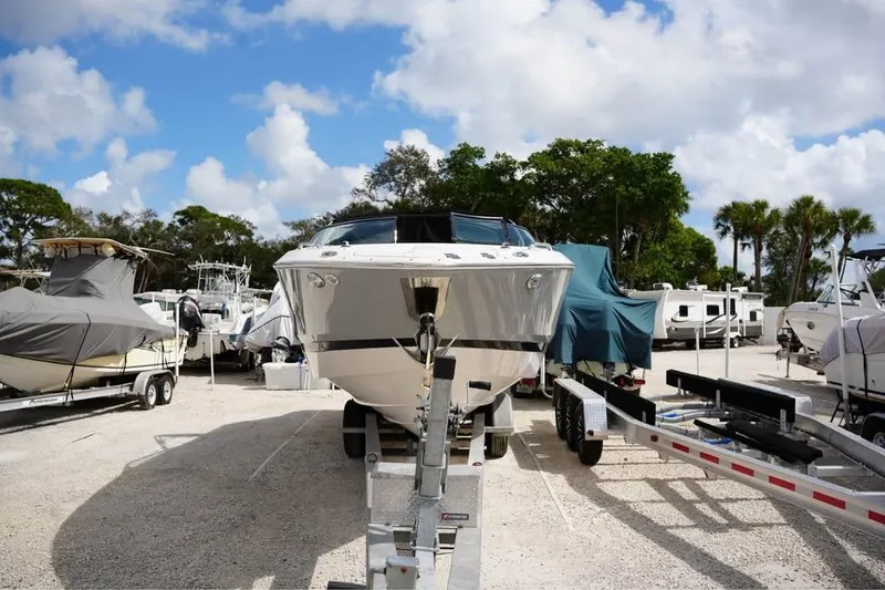 Slide: The Image of 2015 Four Winns H290 boat on trailer in sunny marina setting. - 13