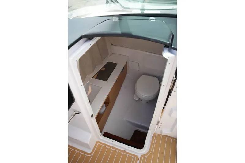 Slide: The Image of 2015 Four Winns H290 boat interior with compact bathroom and wooden accents. - 16