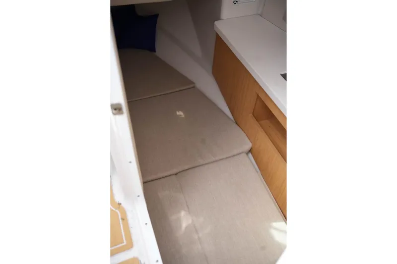 Slide: The Image of 2015 Four Winns H290 cabin interior with beige cushions and wooden cabinetry. - 17