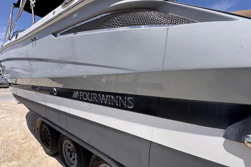 Slide: The Image of 2015 Four Winns H290 boat side view with logo, parked on a trailer. - 21