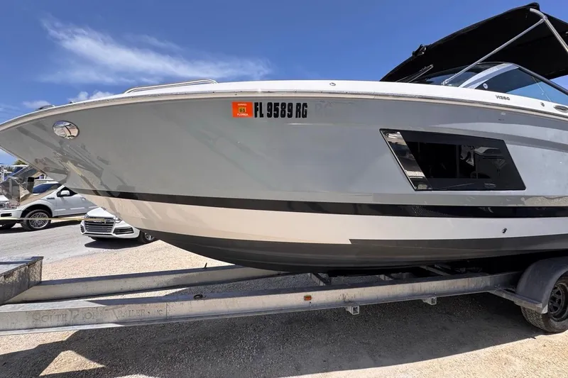 Slide: The Image of 2015 Four Winns H290 boat on trailer, parked outdoors under clear blue sky. - 25