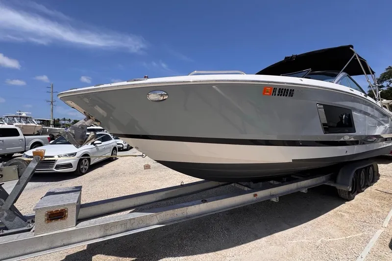 Slide: The Image of 2015 Four Winns H290 boat on trailer under clear blue sky. - 26