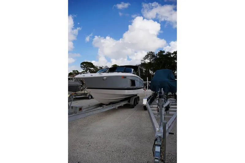 Slide: The Image of 2015 Four Winns H290 boat on trailer under a blue sky. - 3