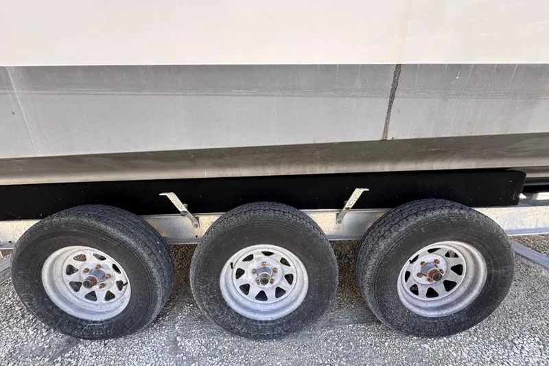 Slide: The Image of Trailer wheels of a 2015 Four Winns H290 boat on gravel surface. - 31