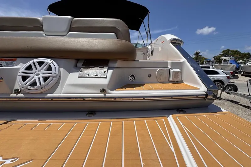 Slide: The Image of 2015 Four Winns H290 boat deck with speaker and seating, under clear blue sky. - 40