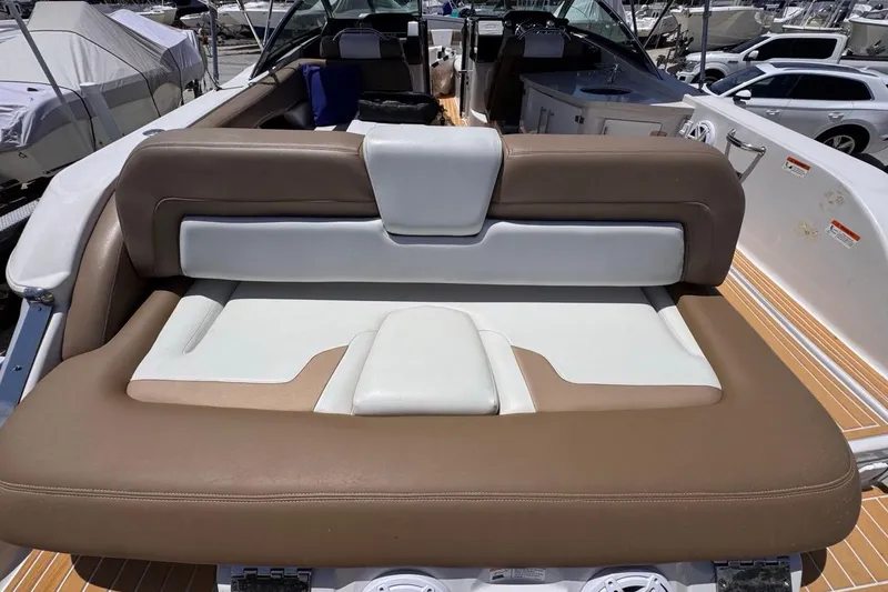 Slide: The Image of 2015 Four Winns H290 boat interior with brown and white seating at a marina. - 42