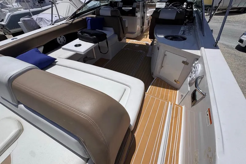 Slide: The Image of 2015 Four Winns H290 boat interior with beige seating, blue cushions, and wooden flooring. - 45