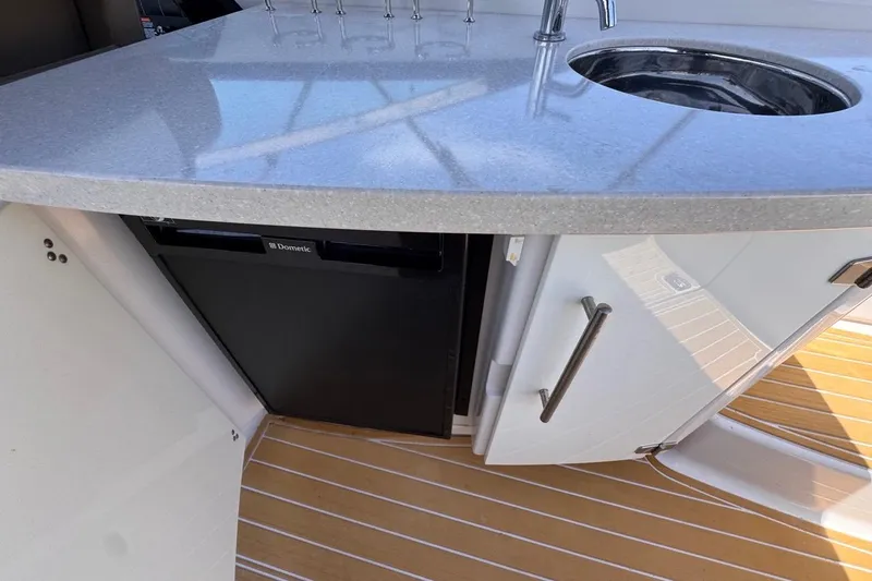 Slide: The Image of 2015 Four Winns H290 boat kitchenette with sink, countertop, and Dometic fridge. - 53