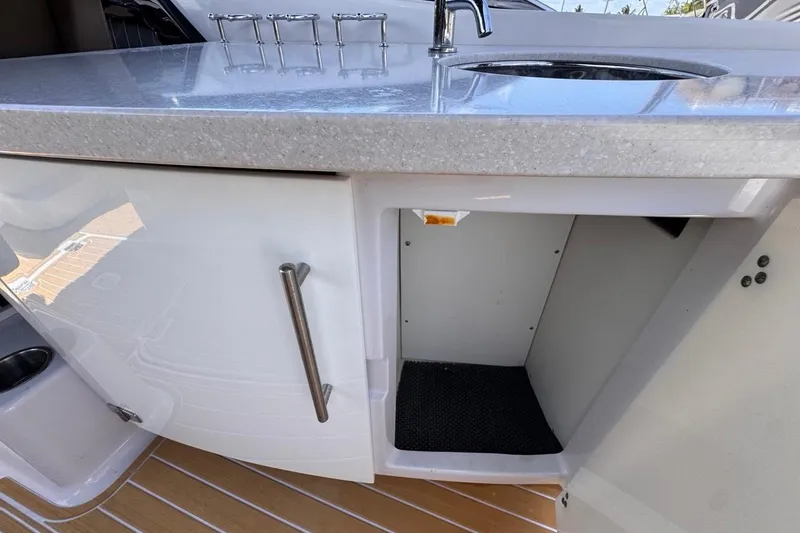 Slide: The Image of 2015 Four Winns H290 boat kitchenette with sink and open storage cabinet. - 55