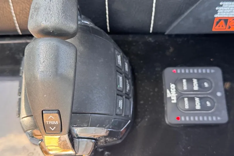 Slide: The Image of Throttle and trim controls on a 2015 Four Winns H290 boat dashboard. - 65