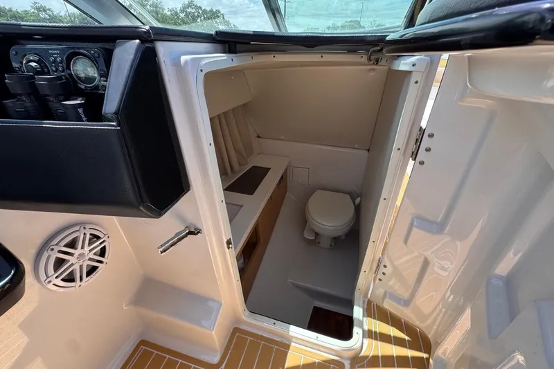 Slide: The Image of 2015 Four Winns H290 boat interior with compact bathroom and control panel. - 67