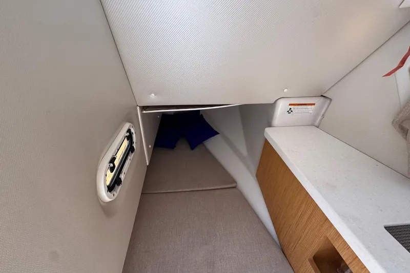 Slide: The Image of Interior cabin of 2015 Four Winns H290 boat, featuring compact sleeping area and storage. - 70