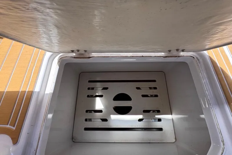 Slide: The Image of Open storage compartment on 2015 Four Winns H290 boat, featuring a slotted drain cover. - 79