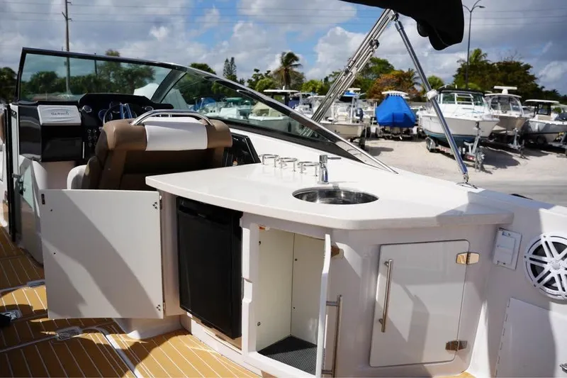 Slide: The Image of Interior of 2015 Four Winns H290 boat with kitchenette and helm, docked under sunny skies. - 9