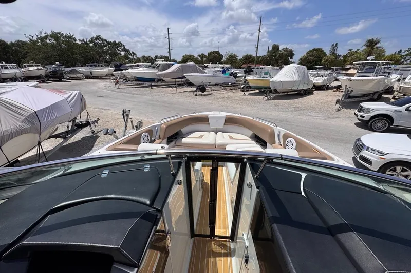 Slide: The Image of 2015 Four Winns H290 boat in a marina with other vessels and cars. - 92