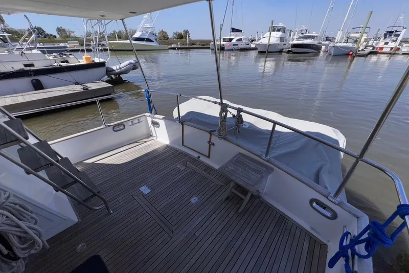 Slide: The Image of 1995 Island Gypsy Eurosedan 32 boat deck at marina, featuring wooden flooring and railing. - 14
