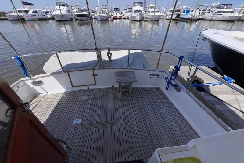 Slide: The Image of 1995 Island Gypsy Eurosedan 32 boat deck at marina, featuring wooden flooring and moored yachts. - 15