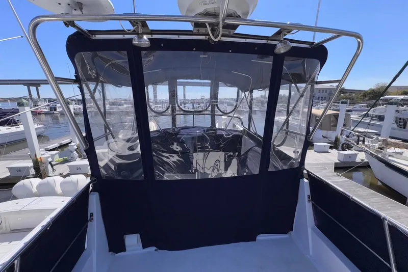 Slide: The Image of 1995 Island Gypsy Eurosedan 32 at marina, featuring enclosed cockpit and clear blue sky. - 19