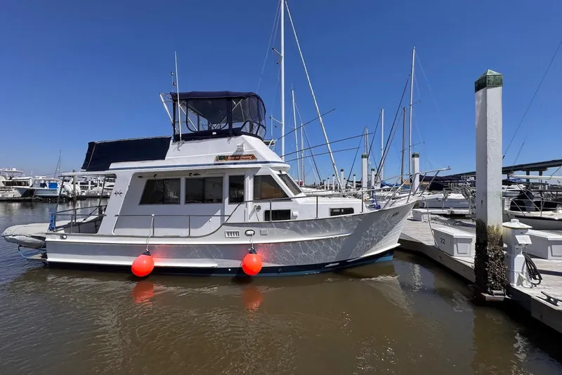 Slide: The Image of 1995 Island Gypsy Eurosedan 32 docked at marina, clear blue sky, vibrant red buoys. - 3