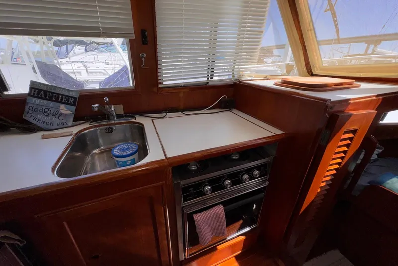 Slide: The Image of 1995 Island Gypsy Eurosedan 32 yacht kitchen with sink, stove, and wooden cabinetry. - 39