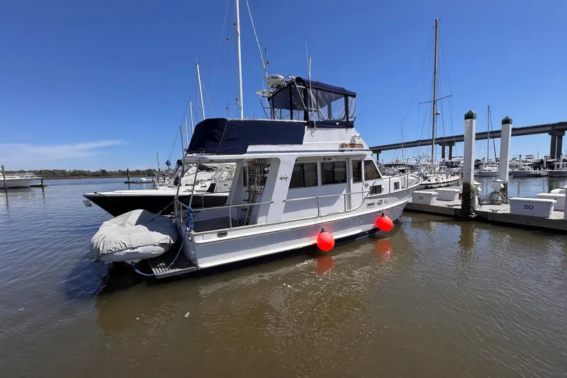 Slide: The Image of 1995 Island Gypsy Eurosedan 32 docked at marina, clear blue sky, calm waters. - 4