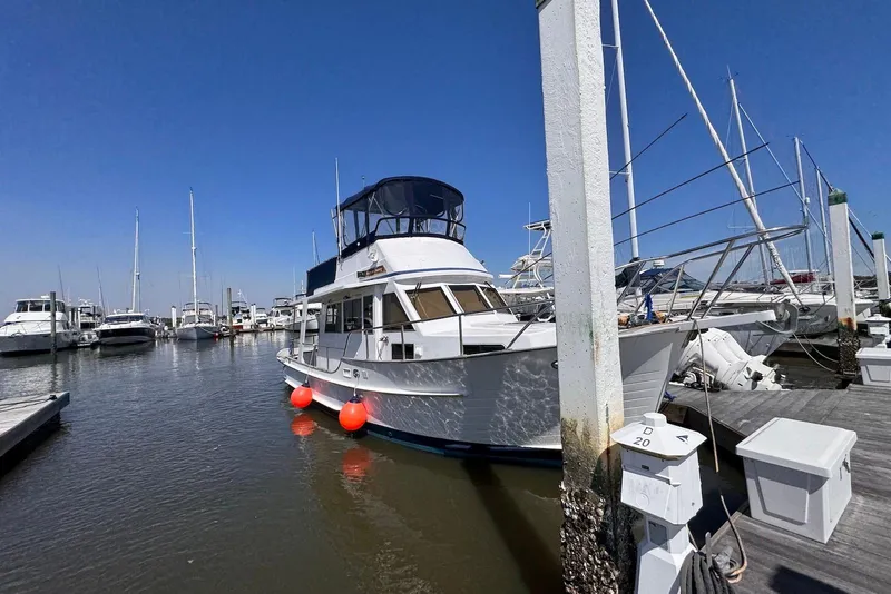 Slide: The Image of 1995 Island Gypsy Eurosedan 32 docked at marina, clear blue sky, calm waters. - 5