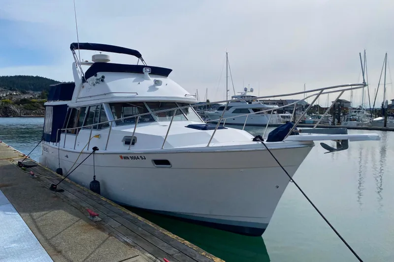 The Image of 1989 Bayliner 3288 Motoryacht docked at a marina, calm water, clear sky. - 0