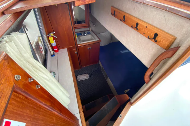 Slide: The Image of 1989 Bayliner 3288 Motoryacht interior with sink, hooks, and cozy sleeping area. - 19