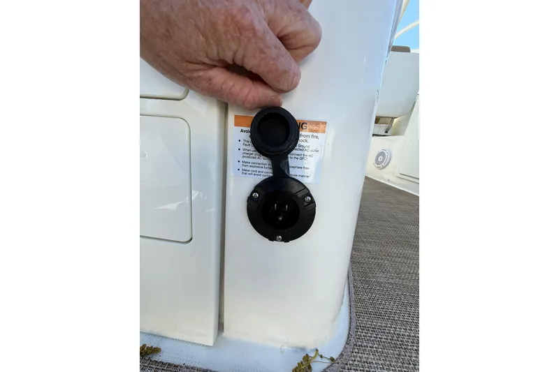 Slide: The Image of Hand opening a power outlet cover on a 2019 World Cat Glacier Bay Edition 2740 Dual Console boat. - 28