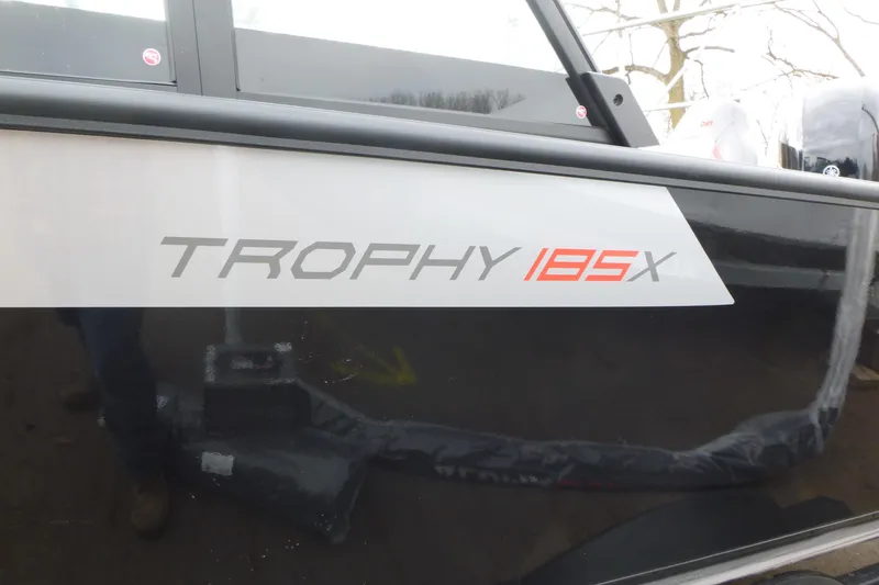 Slide: The Image of 2025 Alumacraft Trophy 185X Sport boat logo on black exterior. - 15