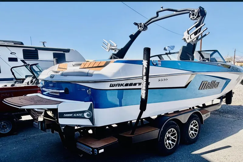 Slide: The Image of 2021 Malibu Wakesetter 23 MXZ boat on trailer, blue and white design, parked outdoors. - 5