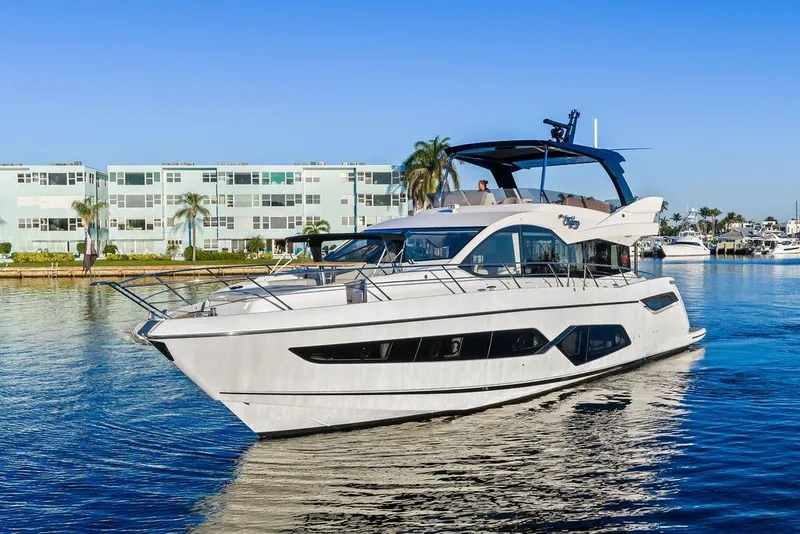 Slide: The Image of 2021 Sunseeker Manhattan 68 yacht cruising near modern waterfront buildings. - 1