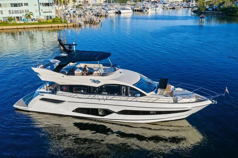 Slide: The Image of 2021 Sunseeker Manhattan 68 yacht cruising in a marina, surrounded by calm waters. - 12