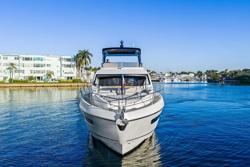 Slide: The Image of 2021 Sunseeker Manhattan 68 yacht on calm water, with buildings and palm trees in the background. - 16