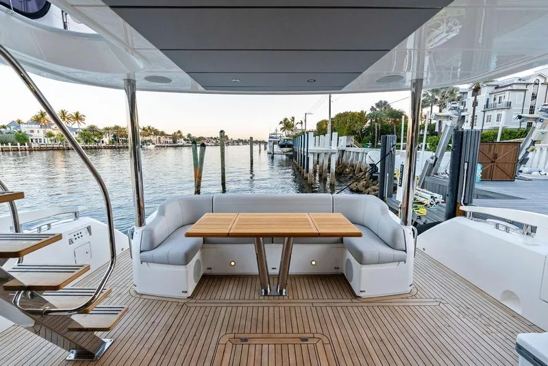 Slide: The Image of Luxurious Sunseeker Manhattan 68 yacht deck with seating and table, docked by waterfront homes. - 23
