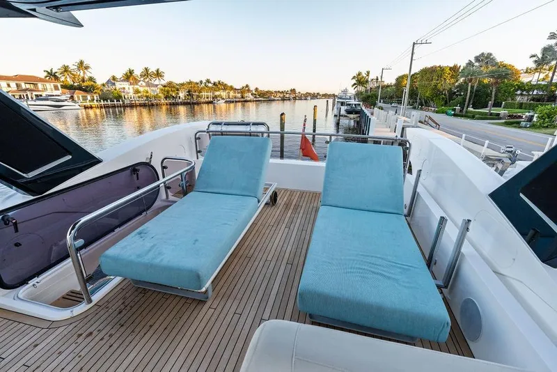 Slide: The Image of Sunseeker Manhattan 68 yacht deck with blue loungers, scenic waterfront view, 2021 model. - 29