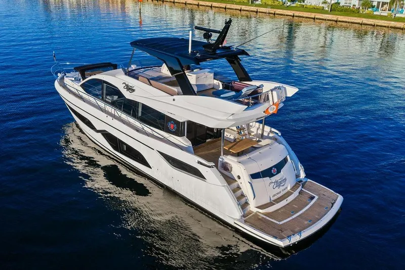 Slide: The Image of 2021 Sunseeker Manhattan 68 yacht on calm water, showcasing luxury design and spacious deck. - 8