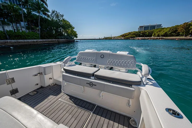 Slide: The Image of 2020 Fountain 38 Center Console boat cruising on clear blue water near lush shoreline. - 12