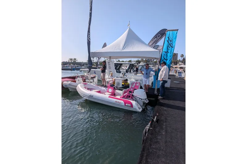Slide: The Image of 2026 Tide Craft Custom Pink & White Catalina 13 displayed at a boat show dock. - 7