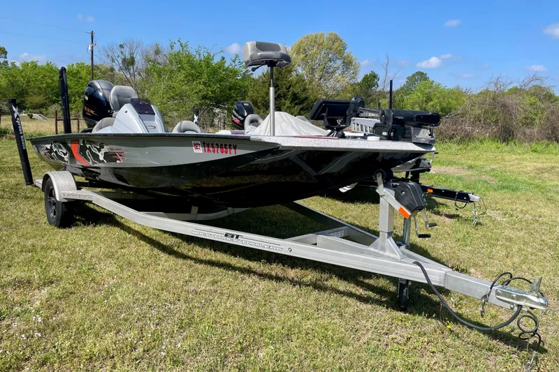 The Image of 2020 Xpress X21 Pro boat on trailer in grassy area, under clear blue sky. - 0