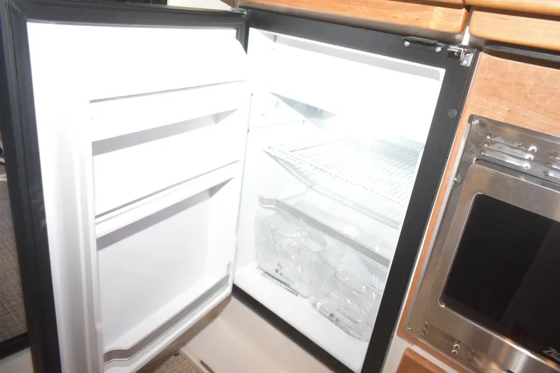Slide: The Image of Open refrigerator inside 2026 Cutwater C-32 CB boat, showcasing interior shelves and storage. - 12