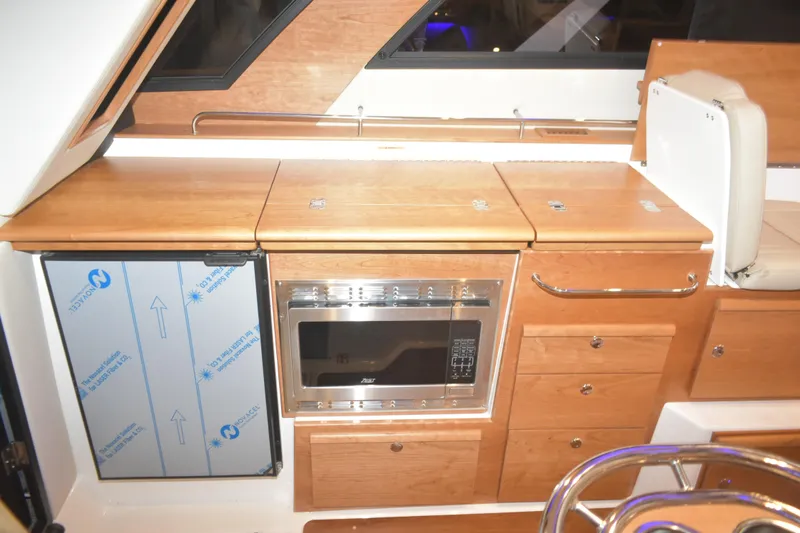 Slide: The Image of 2026 Cutwater C-32 CB interior kitchen with microwave, fridge, and wooden cabinetry. - 14