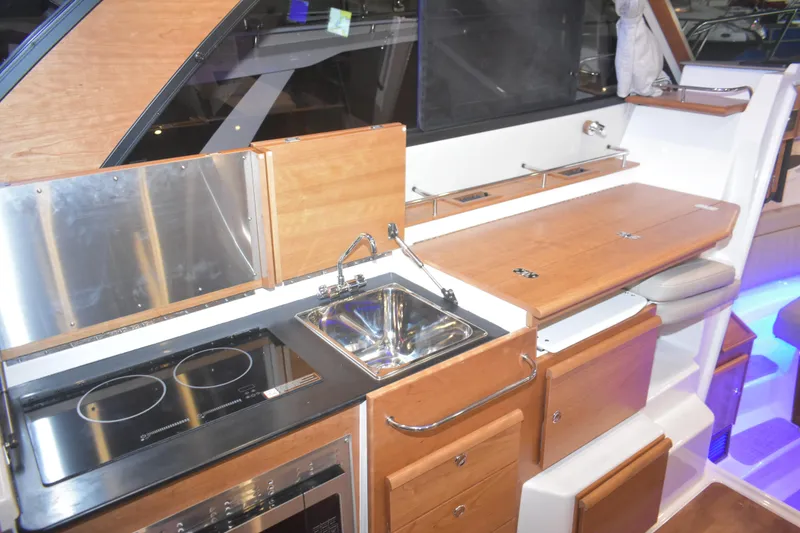 Slide: The Image of 2026 Cutwater C-32 CB yacht kitchen with stove, sink, and wooden cabinetry. - 15