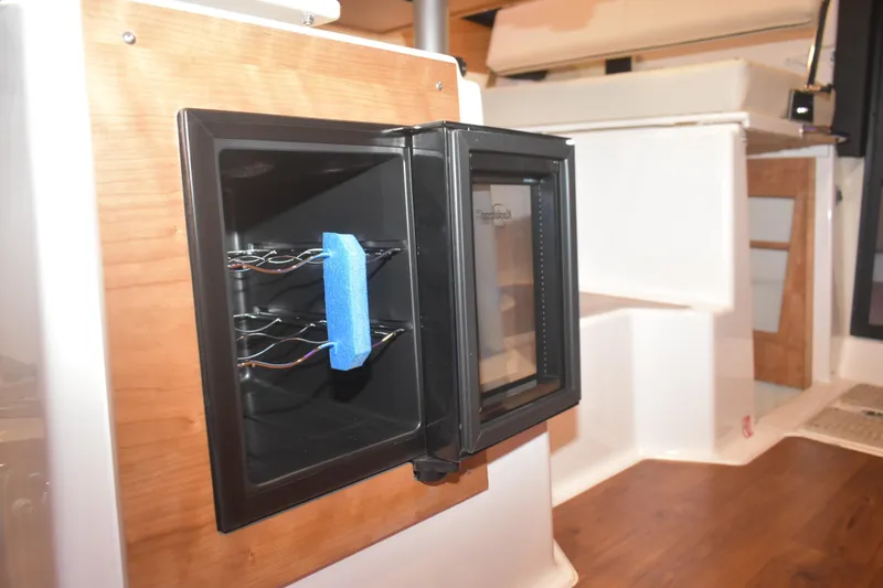 Slide: The Image of Open mini fridge inside 2026 Cutwater C-32 CB boat interior, featuring wooden accents. - 21