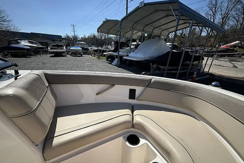 Slide: The Image of 2016 Bayliner 185 Bowrider interior with beige seating, parked in a boatyard. - 18